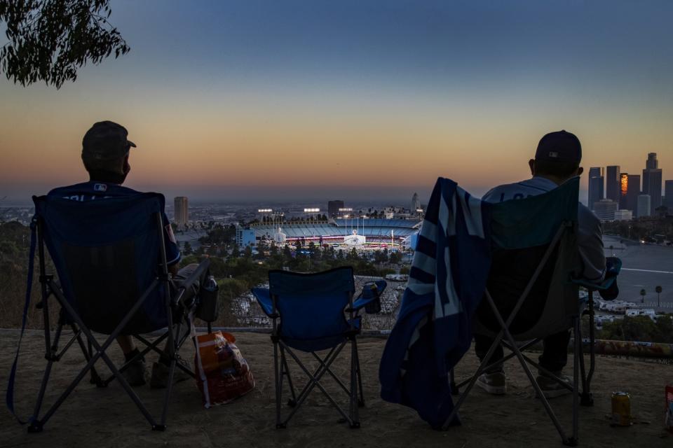People watch Dodger Stadium in the distance at sunset