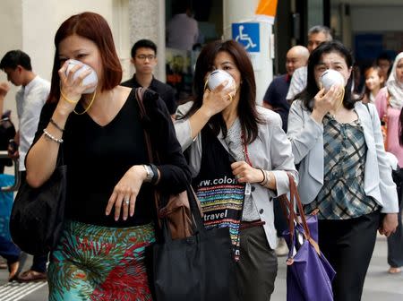 Women cover their faces with masks as haze shrouds Singapore's central business district August 26, 2016. REUTERS/Edgar Su