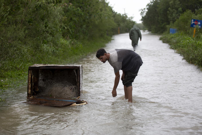 A man leans over next to an oveturned box filled with a fishing line, after Hurricane Ian's storm surge flooded the area in Playa Cajio, Artemisa, Cuba, Tuesday, September 27, 2022. Ian made landfall at 4:30 a.m. EDT Tuesday in Cuba's Pinar del Rio province, where officials set up shelters, evacuated people, rushed in emergency personnel and took steps to protect crops in the nation's main tobacco-growing region. (AP Photo/Ismael Francisco)