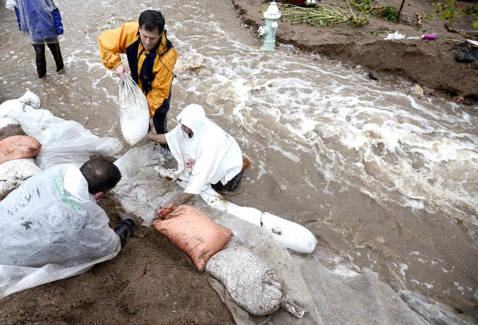 People try to prevent the berm they built from being washed out as water rise in heavy rain in Boulder, Colorado