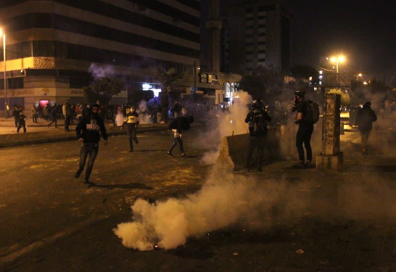 Demonstrators are pictured near smoke rising from tear gas during a protest against the lockdown and worsening economic conditions, amid the spread of the coronavirus disease (COVID-19), in Tripoli