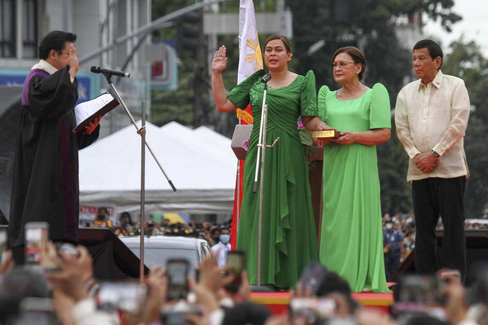 Sara Duterte, second from left, the daughter of outgoing populist president of the Philippines, takes her oath as vice president during rites in her hometown in Davao city, southern Philippines on Sunday, June 19, 2022. Duterte clinched a landslide electoral victory despite her father's human rights record that saw thousands of drug suspects gunned down. Also in photo are, from left, Supreme Court Justice Ramon Paul Hernando, her mother Elizabeth Zimmerman and Philippine President Rodrigo Duterte. (AP Photo/Manman Dejeto)
