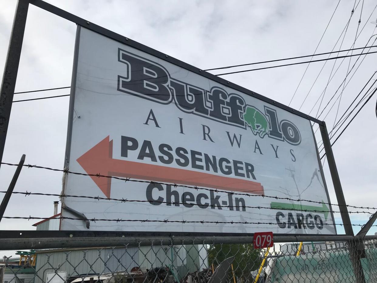 A sign at the intersection of Bristol Avenue and Berry Streets in Yellowknife directs people to the Buffalo Airways' passenger check-in and cargo locations on Aug. 31, 2021. The company is offering discount rates for cargo shipments to Sahtu communities as low water levels impact barge shipments. (Liny Lamberink/CBC - image credit)