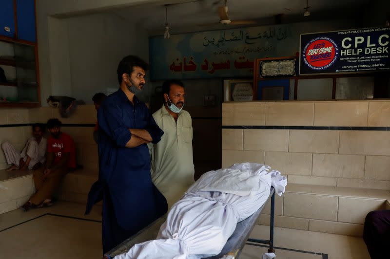 Family members stand beside a body of a relative, who was killed in a plane crash, in Karachi