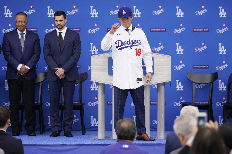 Yoshinobu Yamamoto, center, poses for photos in front of Dodgers manager Dave Roberts, left, and Executive Vice President and General Manager Brandon Gomes, during his introduction as a new member of the Los Angeles Dodgers baseball team Wednesday, Dec. 27, 2023, in Los Angeles. (AP Photo/Ashley Landis)