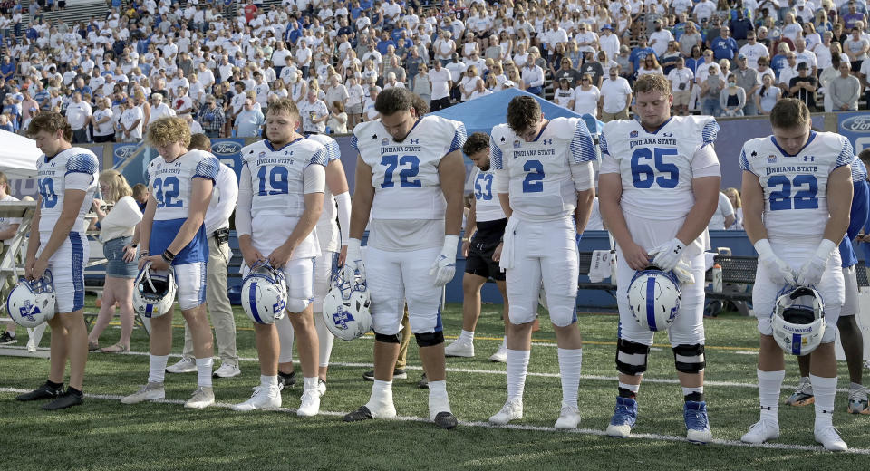 Members of the Indiana State NCAA college football team and fans observe a moment of silence for teammates Caleb VanHooser and Christian Eubanks before the start of the Sycamores' game against North Alabama at Memorial Stadium in Terre Haute, Ind., on Sept. 1, 2022. (Joseph C. Garza/The Tribune-Star via AP)