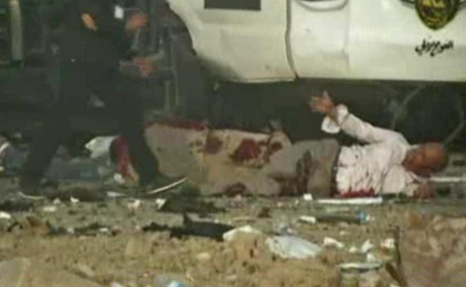 This image made from video shows a wounded man reaching out for help after a series of bombs that exploded Friday, April 25, 2014 at a campaign rally for a Shiite group in Baghdad, Iraq, ahead of the country's parliamentary election. The blasts killed and wounded dozens, officials said. (AP Photo via AP video)