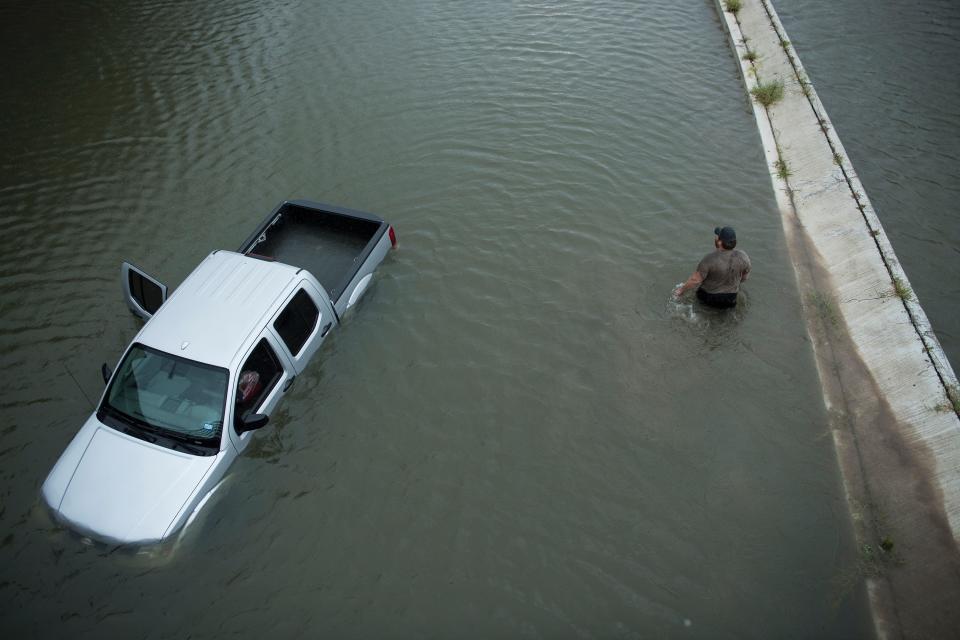 <p>A truck driver walks past an abandoned truck while checking the depth of an underpass during the aftermath of Hurricane Harvey Aug. 28, 2017 in Houston, Texas. (Photo: Brendan Smialowski/AFP/Getty Images) </p>