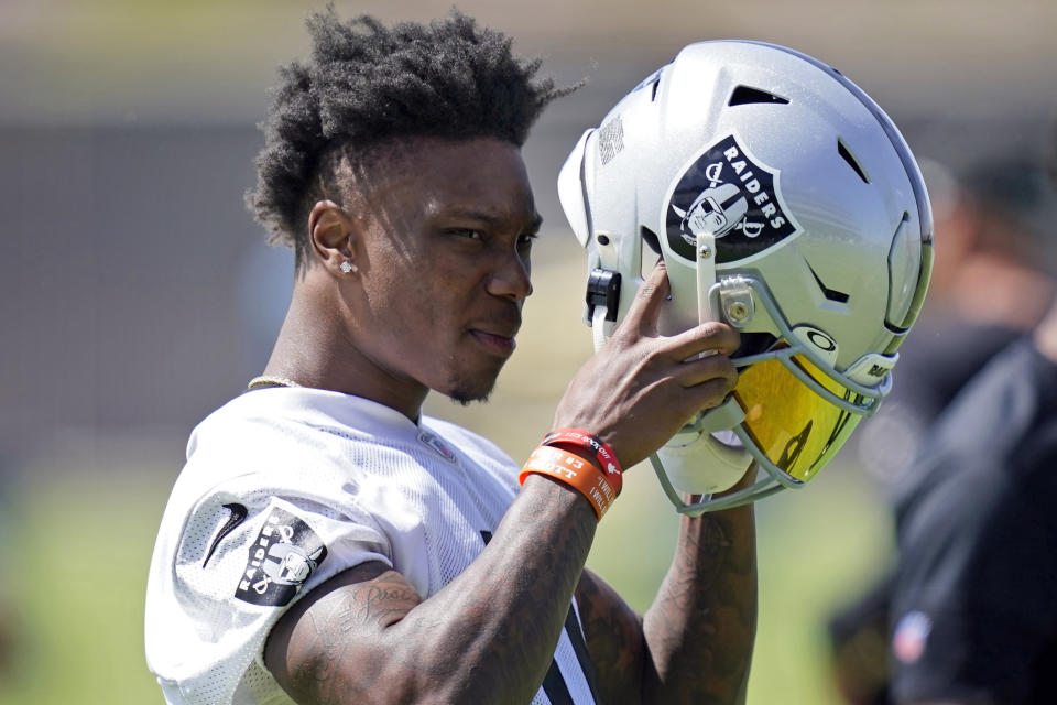 Las Vegas Raiders wide receiver Henry Ruggs III (11) puts on his helmet during NFL football practice, Wednesday, June 2, 2021, in Henderson, Nev. (AP Photo/John Locher)