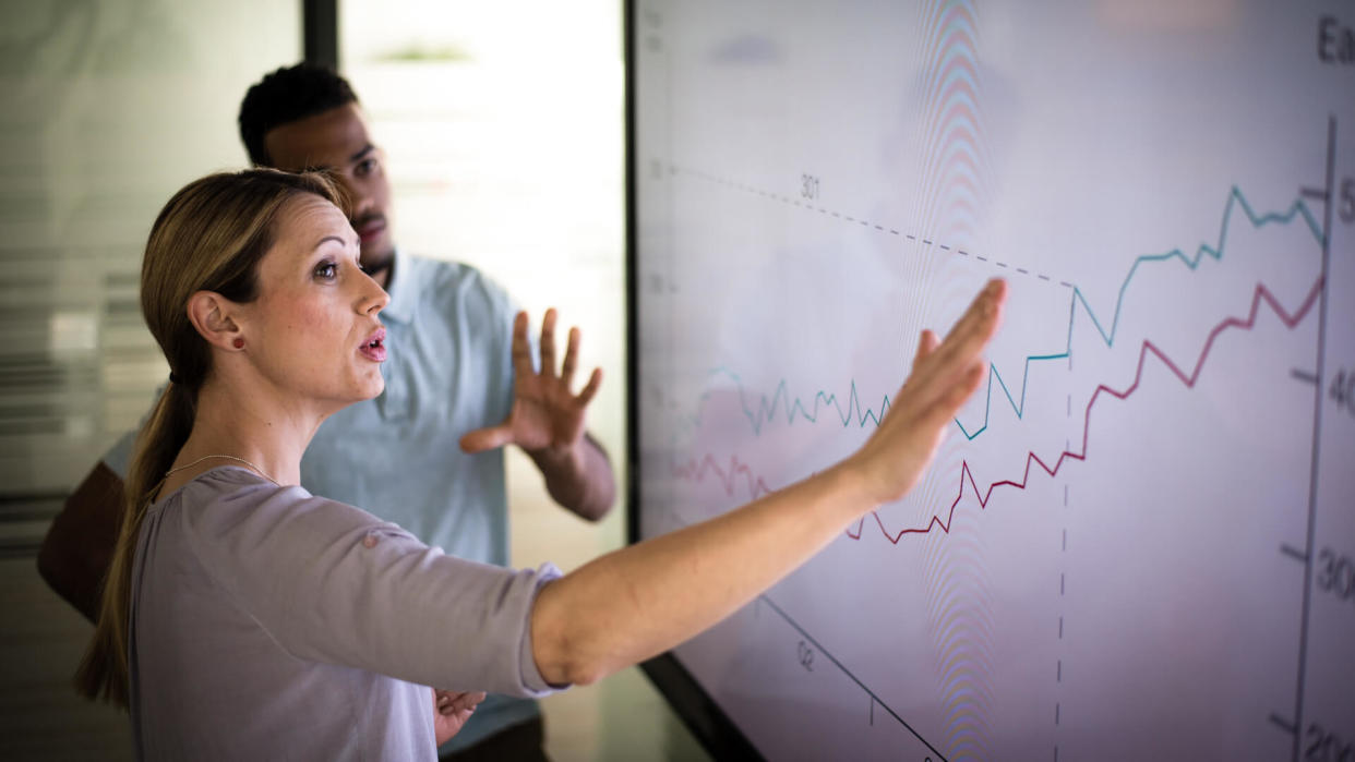 Businesswoman explaining graph to his coworker in conference room.