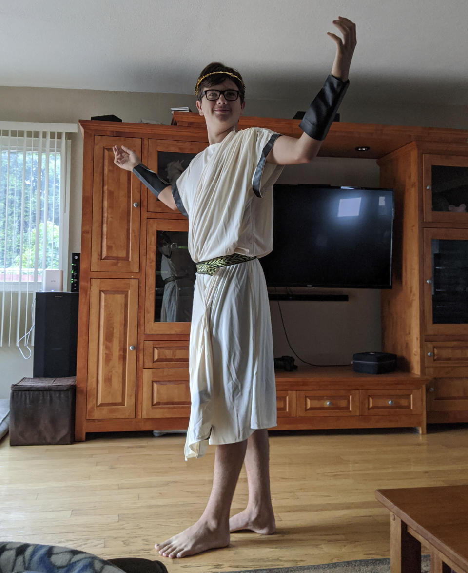 In this Aug. 28, 2020, photo provided by Meredith Christensen-Houghtelling, her son, Logan Houghtelling, poses for a photo in a toga and a golden leaf crown before attending a virtual class in San Lorenzo, Calif. (Meredith Christensen-Houghtelling via AP)