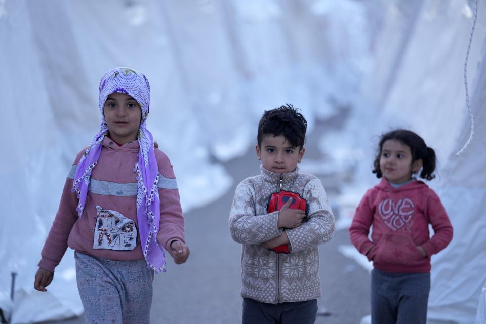 Children walk between tents, in Aslanli, southeastern Turkey, Thursday, Feb. 9, 2023. Tens of thousands of people who lost their homes in a catastrophic earthquake huddled around campfires in the bitter cold and clamored for food and water Thursday, three days after the temblor hit Turkey and Syria. (AP Photo/Kamran Jebreili)