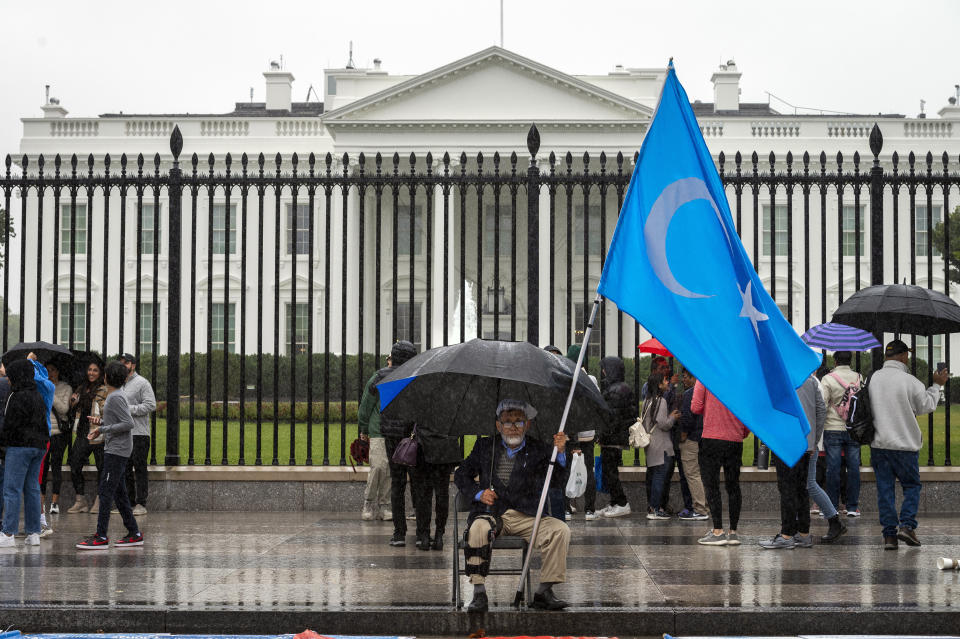 A member of the District of Columbia's Uyghur community sits in the rain as the East Turkistan Awakening Movement holds a rally outside the White House against the Chinese Communist Party (CCP) to coincide with the 73rd National Day of the People's Republic of China in Washington, Saturday, Oct. 1, 2022. They protest against alleged oppression by the Chinese government against Uyghurs and other mostly Muslim ethnic groups in far-western Xinjiang province. China's government has been accused of human rights abuses against Uyghurs and other predominantly Muslim minorities in the region. (AP Photo/Cliff Owen)