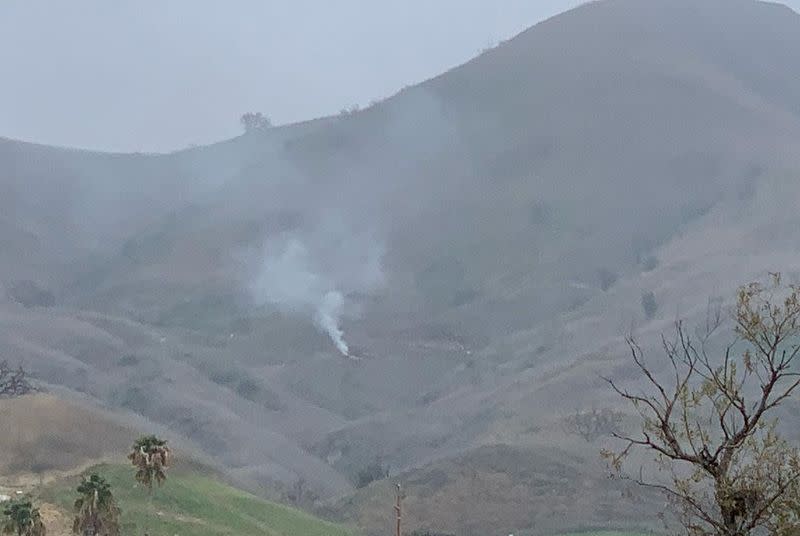 Smoke rises amid foggy weather from the site of a helicopter crash that killed former NBA star Kobe Bryant along a hillside in Calabasas