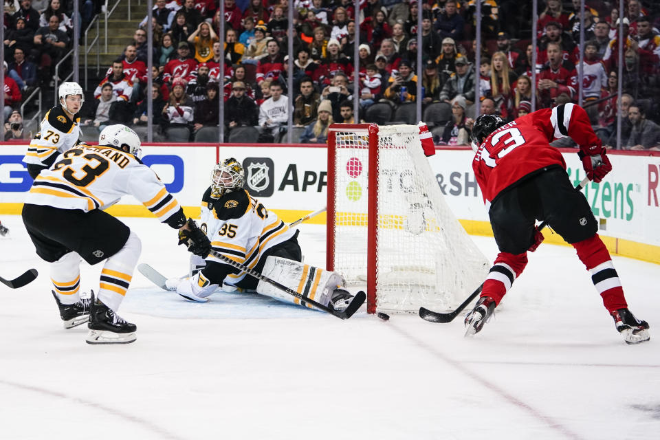 Boston Bruins' Brad Marchand (63) and goaltender Linus Ullmark (35) stops a shot on goal by New Jersey Devils' Nico Hischier (13) during the first period of an NHL hockey game Wednesday, Dec. 28, 2022, in Newark, N.J. (AP Photo/Frank Franklin II)