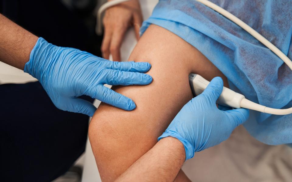 doctor doing ultrasound exam to woman's legs in hospital