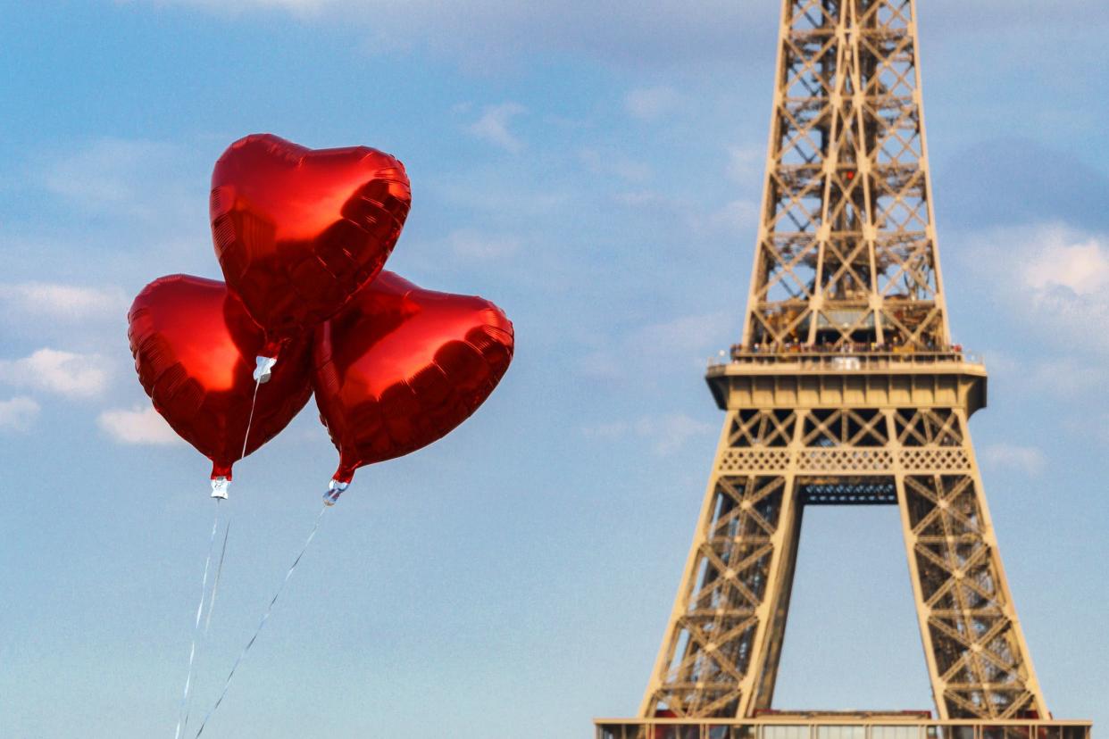 heart-shaped balloons floating with eiffel tower in the distance