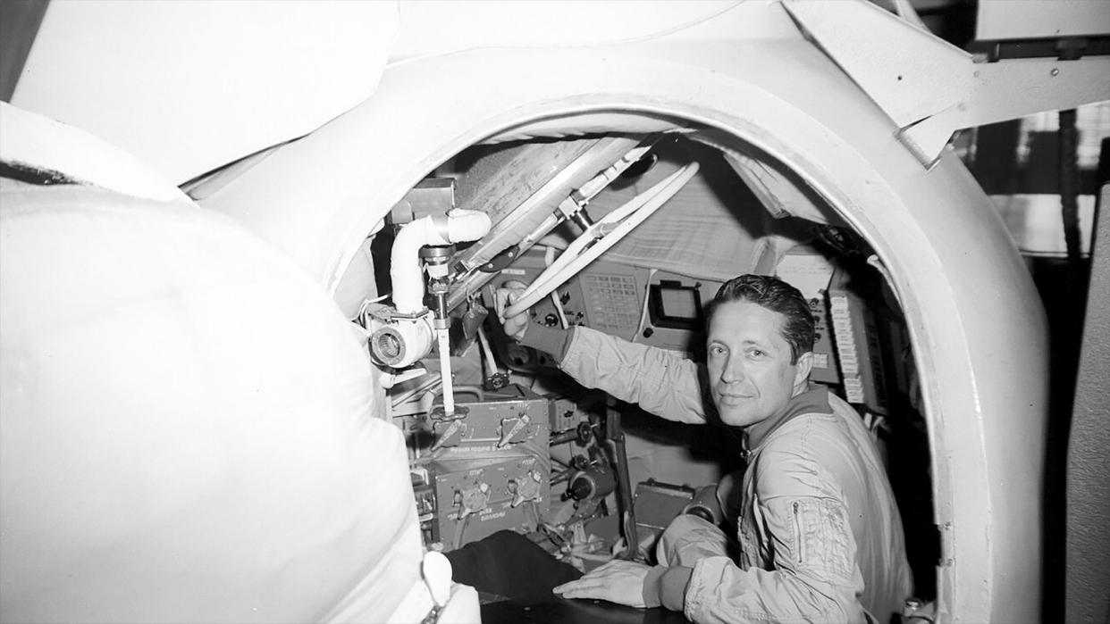  Black and white photo of a man inside a mock space capsule. 