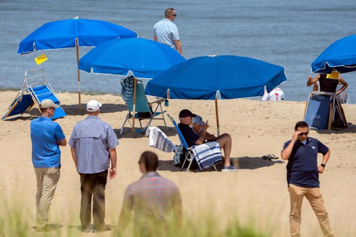 President Joe Biden and first lady Jill Biden sit underneath an umbrella surrounded by Secret Service agents on a beach in Rehoboth Beach on Wednesday, Aug. 2, 2023.
