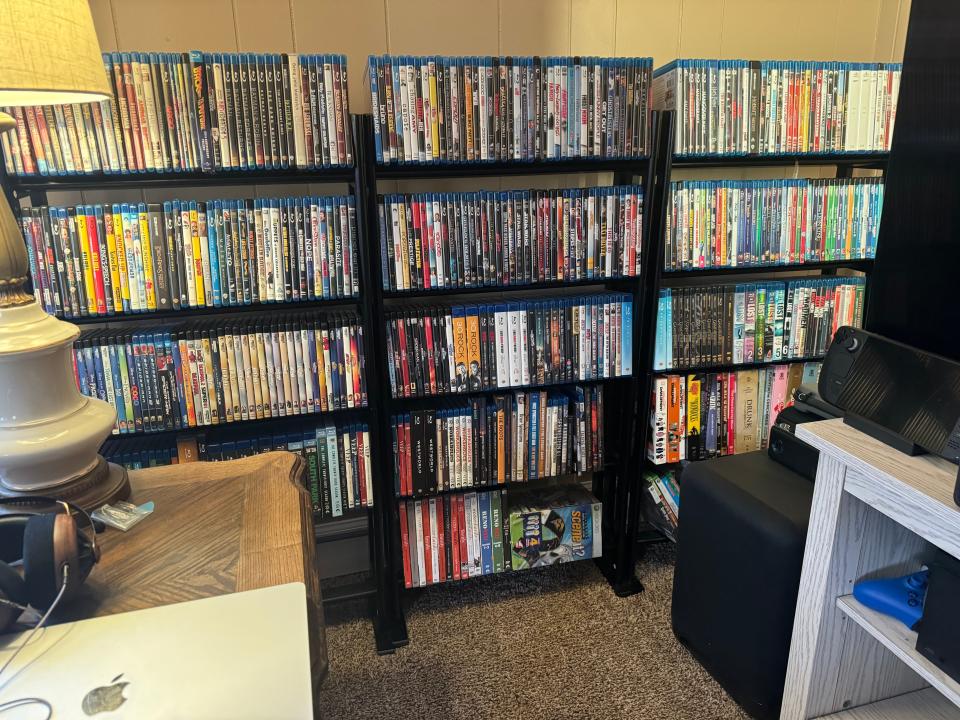 three bookshelves full of dvds and blurays, in a home office. there are approximately 500 discs