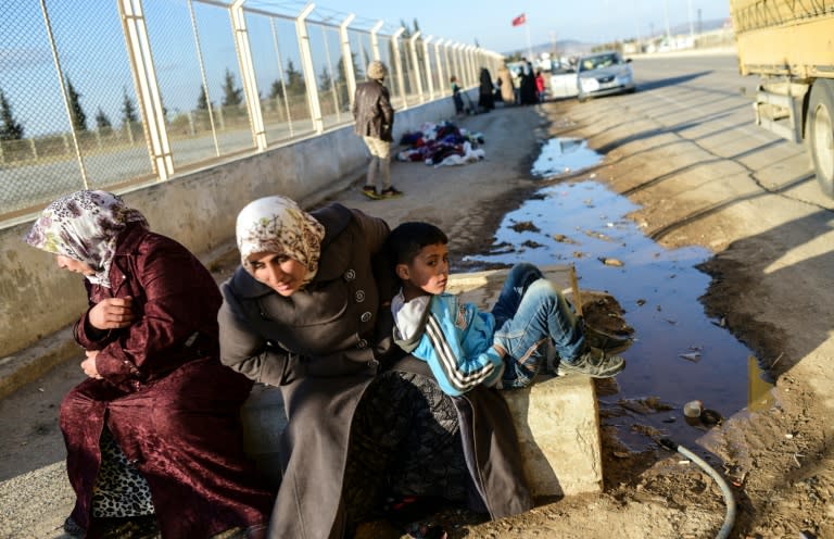 Two Syrian women and a boy wait in front of Oncupinar crossing gate, near the town of Kilis, to return to Syria on February 9, 2016