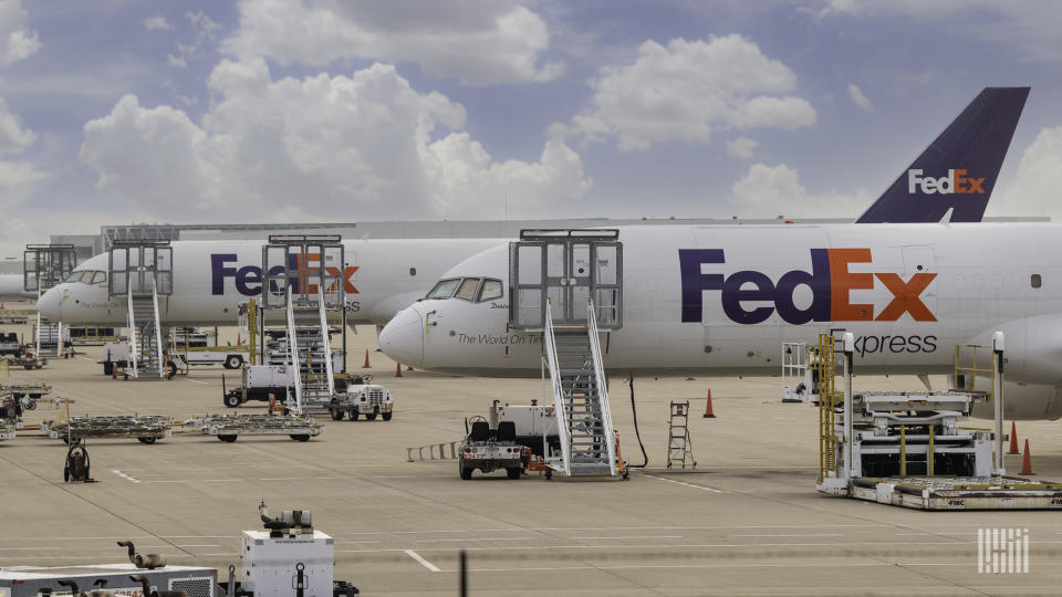 Purple-tailed FedEx cargo planes waiting on the tarmac, with ladders up to pilot door.