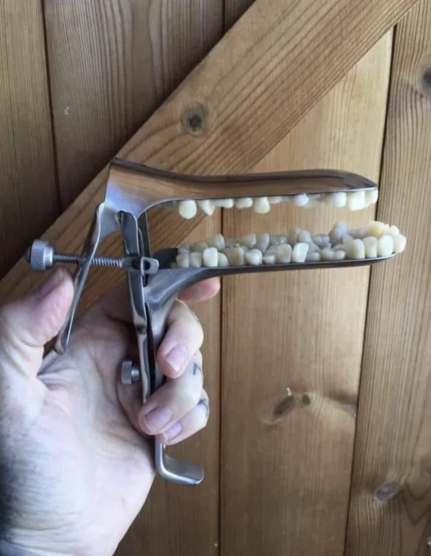 A hand holds a vintage metal manual bean slicer with beans inside against a wooden background