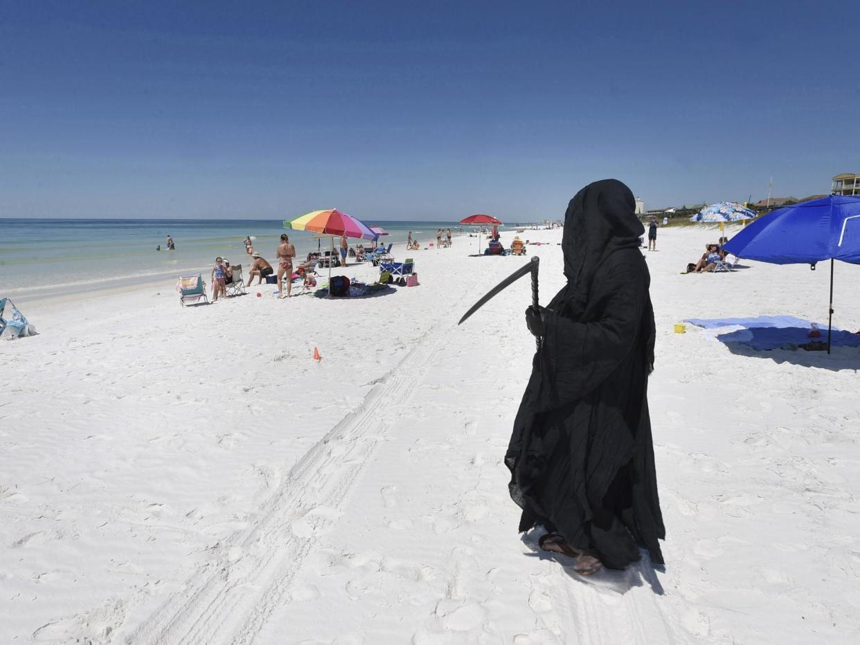 Florida Attorney Daniel Uhlfelder, dressed as the Grim Reaper, walks the newly-opened beach near Destin, Florida, on 1 May, 2020. (Devon Ravine/Northwest Florida Daily News via AP)