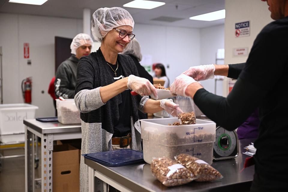 Volunteer Henri Montgomery joins others as they fill bags of nuts at the Utah Food Bank and talks about the products and items they have for those that need them, at their South Salt Lake warehouses on Thursday, Dec. 28, 2023. | Scott G Winterton, Deseret News