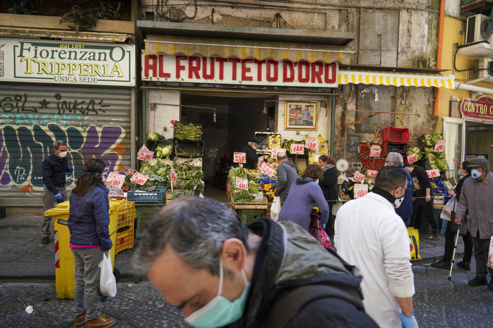 People buy fruit and vegetables at a shop in Naples, Monday, April 27, 2020. Region Campania allowed cafes and pizzerias to reopen for delivery Monday, as Italy is starting to ease its lockdown after a long precautionary closure due to the coronavirus outbreak. (AP Photo/Andrew Medichini)