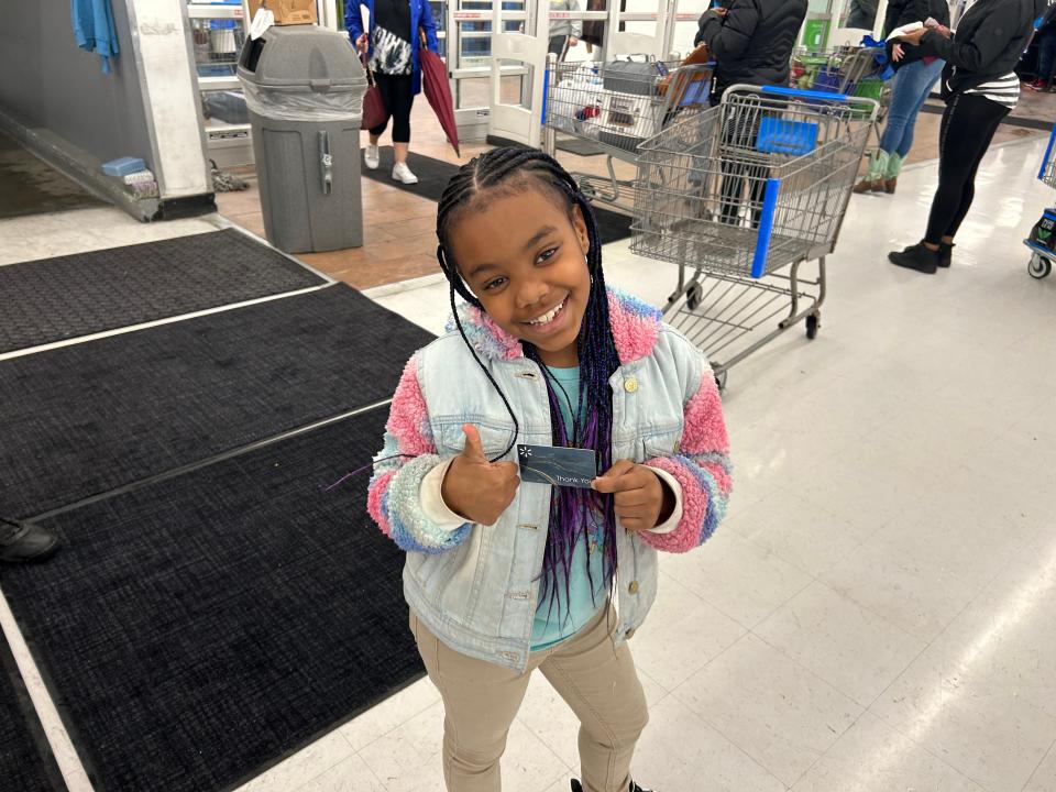 Eight-year-old Sorea Clanton, a student at Pleasants Lane Elementary School in Petersburg, gives a thumbs-up as she holds a $250 gift card Thursday, Dec. 22, 2022 at Walmart in Colonial Heights. Sorea and her fellow Petersburg students took part in the 'Shop with a Hero' program where they were accompanied by first-responders in picking out gifts for Christmas.