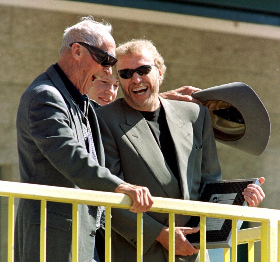 FILE - Former University of Oregon track coach Bill Bowerman shares a laugh with Nike CEO and Oregon alumni Phil Knight as Knight presents him with an award at Hayward Field during the Prefontaine Classic track meet in Eugene, Ore., in this May 30, 1999, file photo. Ever since track coach named Bill Bowerman tinkered with the idea of pouring rubber into his waffle iron to concoct a better shoe sole for running, Nike and track have grown together. (AP Photo/John Gress, File)