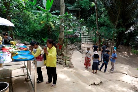 Women pray at a ceremony for members of the Wild Boars soccer team, during their return to the Tham Luang caves where they were trapped in a year ago, in Chiang Rai