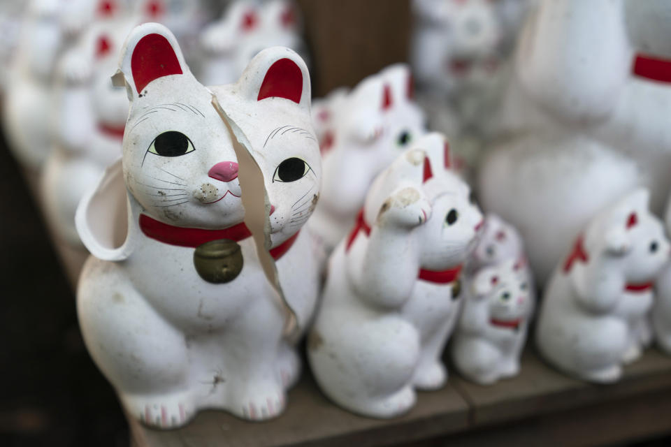 In this June 25, 2019, photo, a broken beckoning cat figurine sits on a shelf at Gotokuji Temple in Tokyo. According to a centuries-old legend provided by the temple, Gotokuji, a Buddhist temple located in the quiet neighborhood of Setagaya, is the birthplace of beckoning cats, the famous cat figurines that are widely believed to bring good luck and prosperity to home and businesses. Some visitors come just to snap a few photos, while others make a trip to the temple to pray and make wishes. (AP Photo/Jae C. Hong)