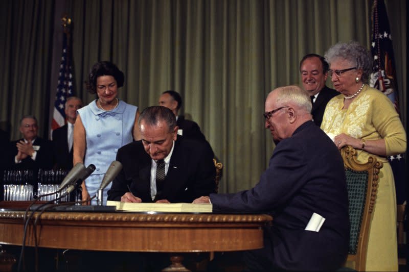 President Lyndon B. Johnson (2nd L) signs the Medicare bill July 30, 1965, at the Harry S. Truman Library in Independence, Mo. Former President Harry S. Truman (2nd R), first lady Claudia Alta "Lady Bird" Johnson (L) and former first lady Bess Truman (R) look on. File Photo courtesy the White House Press Office