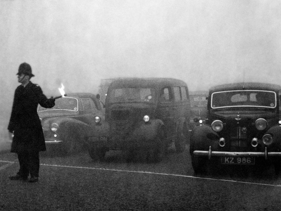 A policeman used a flare to guide cars through traffic during the Great Smog in 1952.