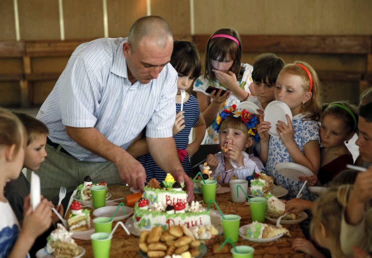 Children wait before taking a piece of a cake during a birthday party in Ukraine, July 30, 2015. (Reuters)