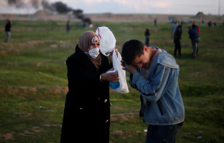 A woman helps a Palestinian boy after inhaling tear gas fired by Israeli troops during a protest at the Israel-Gaza border fence, east of Gaza City February 22, 2019. REUTERS/Mohammed Salem