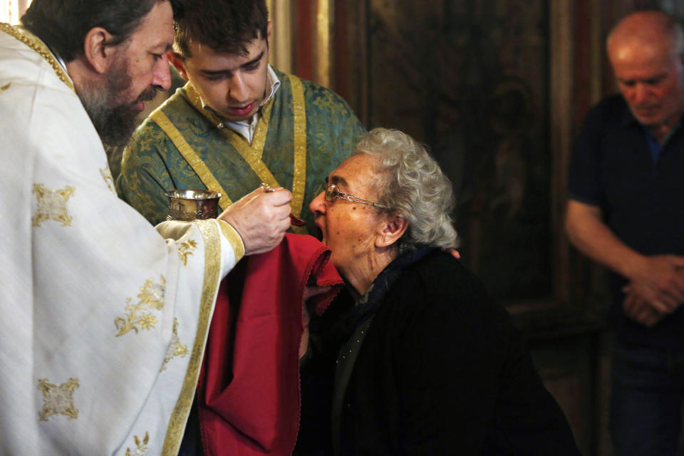 In this Sunday, May 24, 2020, photo, a Greek Orthodox priest distributes Holy Communion during Sunday Mass in the northern city of Thessaloniki, Greece, using the traditional method of a shared spoon. Contrary to science, the Greek Orthodox Church and its followers insist it is impossible for any disease, including the coronavirus, to be transmitted through Holy Communion. (AP Photo/Giannis Papanikos)