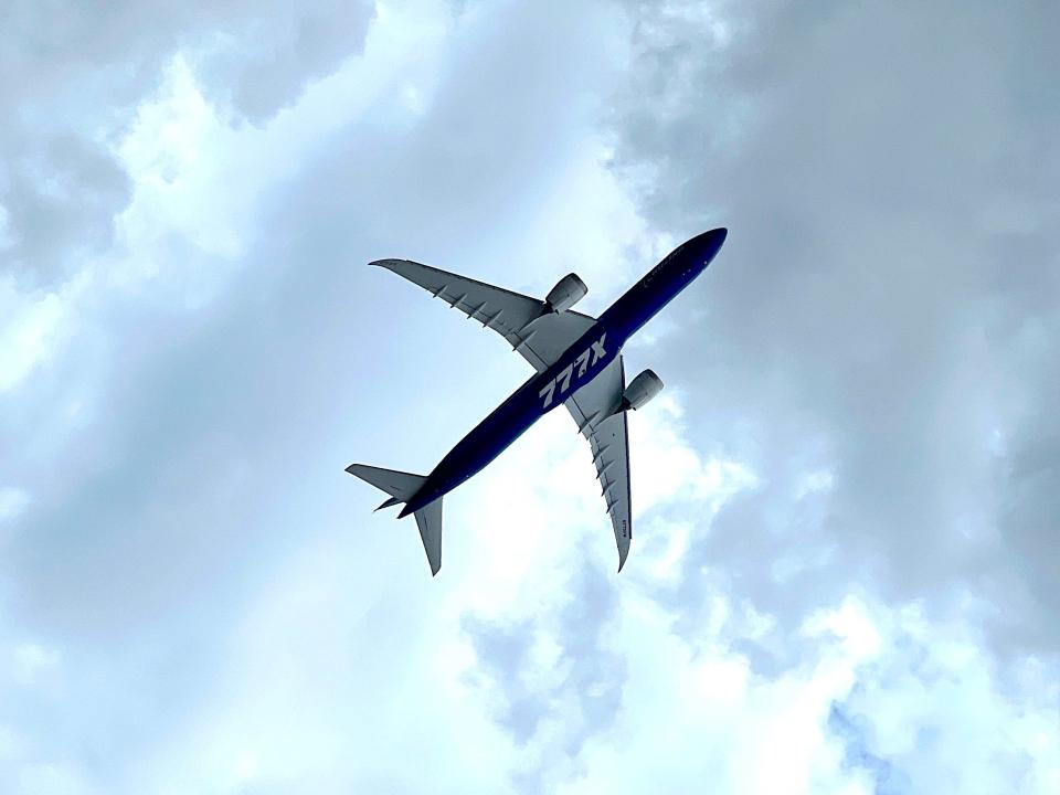 A Boeing 777-9 seen from below with 777X written on the undercarriage, flying close to the ground at the Paris Air Show