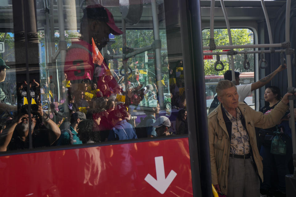 Un pasajero observa desde un autobús a un grupo de feministas que se manifiestan contra un borrador para la nueva Constitución, en Santiago, Chile, el 14 de diciembre de 2023. Los chilenos tienen hasta el 17 de diciembre para estudiar sus artículos y decidir si sustituye a la actual, impuesta por la dictadura militar hace 41 años, o si prefieren otra vía para el cambio. (AP Foto/Esteban Félix)