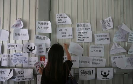 A woman looks at notes posted on a board following protests against the proposed extradition bill, in Hong Kong