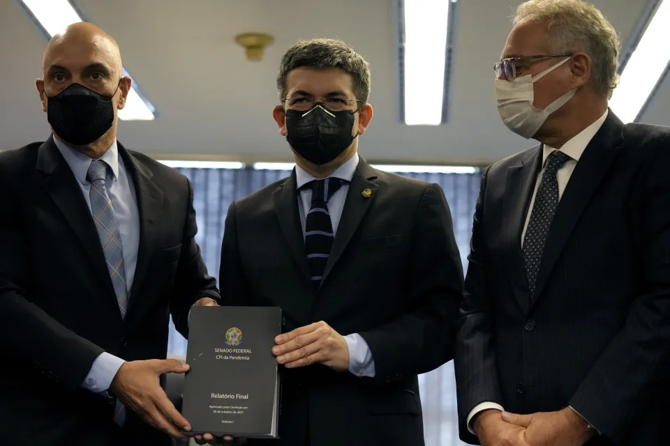 Brazilian Supreme Court Justice Alexandre de Moraes, left, poses for photos as he receives a final report from members of a Senate inquiry committee that investigated the government&#x002019;s handling of the COVID-19 pandemic, Randolfe Rodrigues, center, and Renan Calheiros, at the Supreme Court in Brasilia, Brazil, Wednesday, Oct. 27, 2021. A Brazilian Senate committee has recommended that President Jair Bolsonaro face a series of criminal indictments for actions and omissions related to the world&#39;s second highest COVID-19 death toll. (AP Photo/Eraldo Peres)