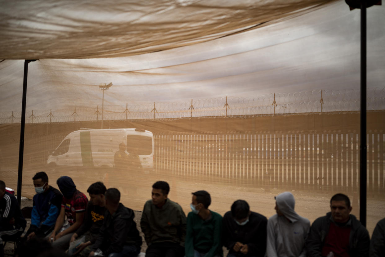 Agentes de la Oficina de Aduanas y Protección Fronteriza de Estados Unidos caminan entre la barrera fronteriza y los migrantes que esperan a ser procesados por agentes de la Oficina de Aduanas y Protección Fronteriza de Estados Unidos en el nuevo centro de procesamiento móvil debajo de la circunvalación Loop 375, el viernes 7 de octubre de 2022, en El Paso, Texas. (Ivan Pierre Aguirre para The New York Times).