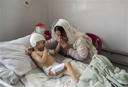 Abuzar, the son of Afghan journalist Sardar Ahmed of Agence France-Presse (AFP) who was killed with his wife and two children during an attack by gunmen at Serena Hotel, is comforted by his grandmother at the Emergency hospital in Kabul March 27, 2014. REUTERS/Zohra Bensemra