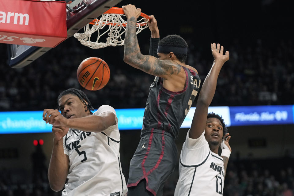 Oklahoma guard Rivaldo Soares, center, dunks the ball as he gets between Central Florida forward Omar Payne (5) and forward Marchelus Avery (13) during the first half of an NCAA college basketball game, Saturday, Feb. 3, 2024, in Orlando, Fla. (AP Photo/John Raoux)