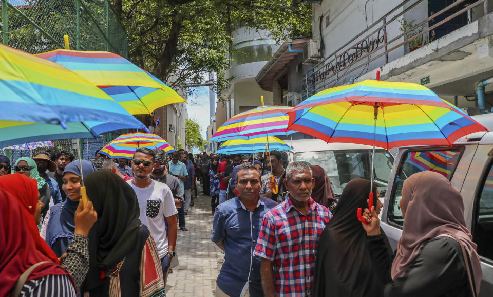 Maldivians hold colorful umbrellas as they wait in the sun to caste their vote during presidential election day in Male, Maldives, Sunday, Sept. 23, 2018. (AP Photo/Mohamed Sharuhaan)