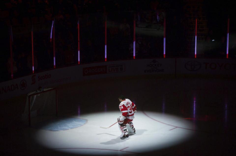 Detroit Red Wings' goalie Petr Mrazek, of the Czech Republic, is illuminated by a spotlight as he skates to his net after the singing of the national anthems before the team's NHL hockey game against the Vancouver Canucks on Tuesday, Feb. 28, 2017, in Vancouver, British Columbia. (Darryl Dyck/The Canadian Press via AP)