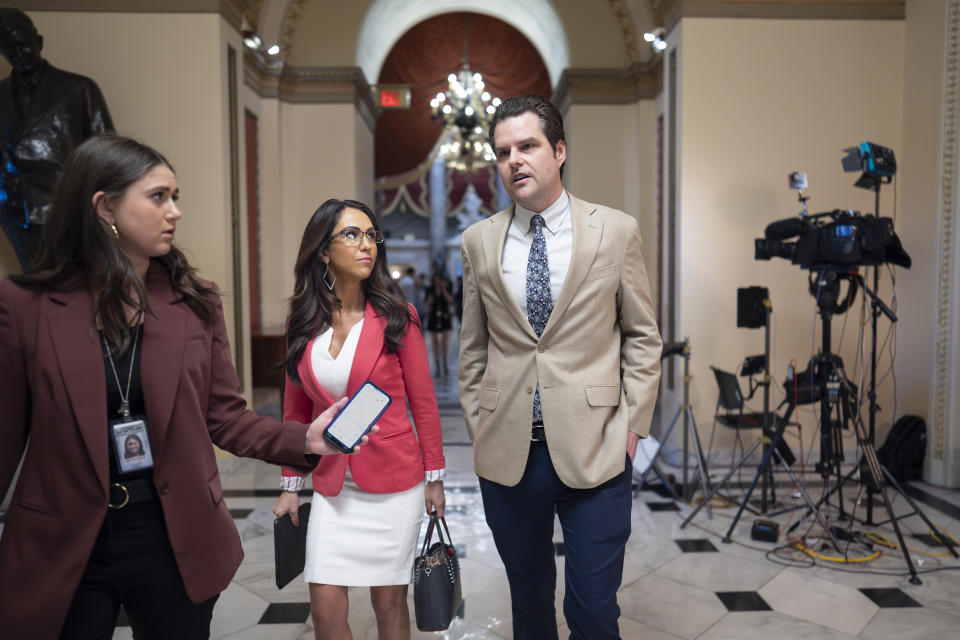 Rep. Lauren Boebert, R-Colo., center, and Rep. Matt Gaetz, R-Fla., walk with a reporter, left, at the Capitol in Washington, Thursday, April 18, 2024. (AP Photo/J. Scott Applewhite)