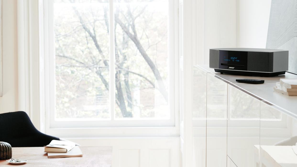 Bose Wave set on a media console in a living room with remote nearby. 